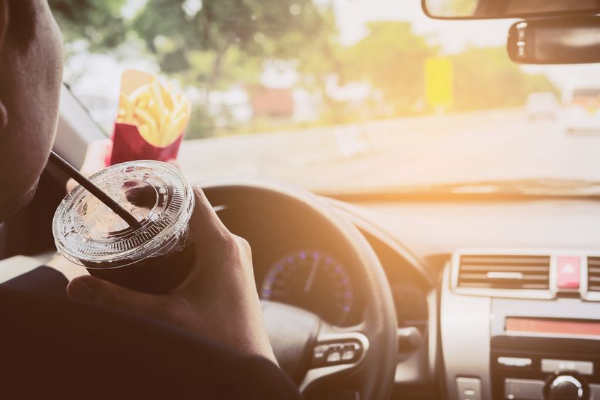 79500434_s Man driving car while eating French fries and soft drink with potential for car accident