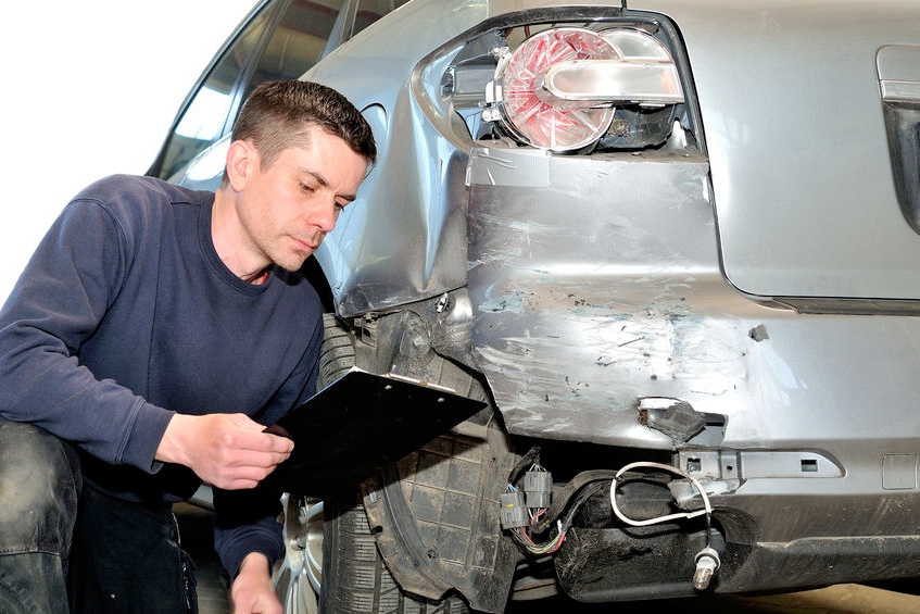 Estimator inspecting collision damage before preparing repair options