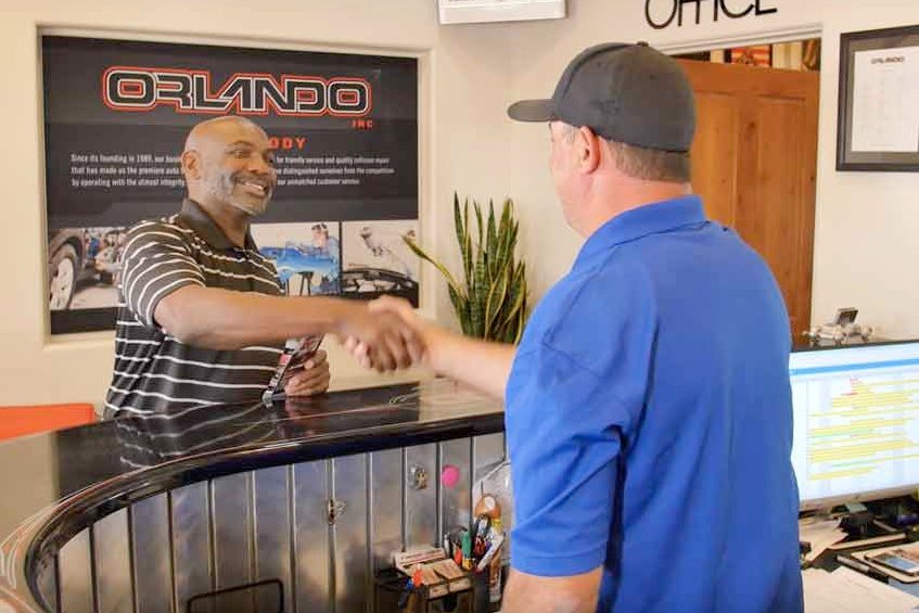 Orlando Auto Body team member greeting a customer inside the Mesa office