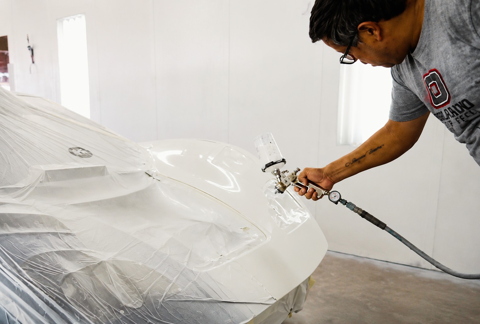 Orlando Auto Body refinishing technician working inside a paint booth